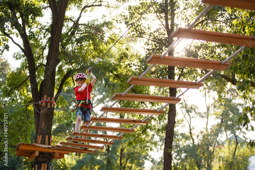 child climbs in a rope park. Boy In Adventure Park having fun in high wire park. Toddler Boy On A Ropes Course. Male toddler on zip line. Boy having a fun on Climbing Frame. Boyscout on a tree. Summer