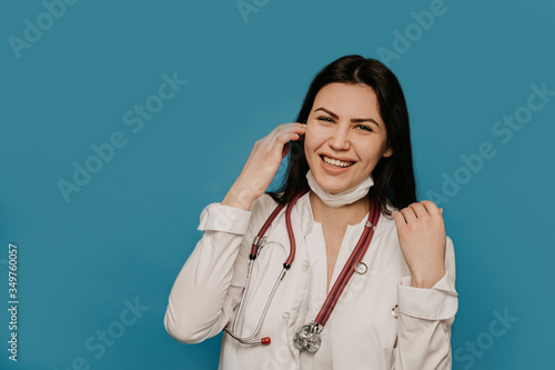 Female doctor with phonendoscope on her neck dressed in a medical gown, smiling broadly, satisfied receive good news about her patient, one more saved life. Covid-19 virus concept.