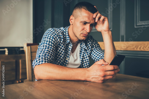 Worried male browsing phone in cafe