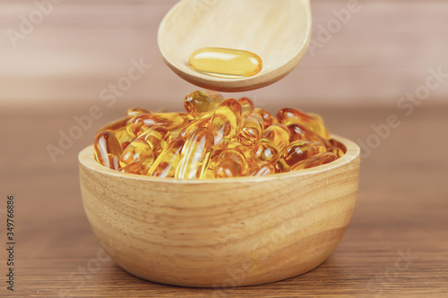 A pile of cod liver oil capsule in a wooden spoon. Dietary supplement for health-care concepts.