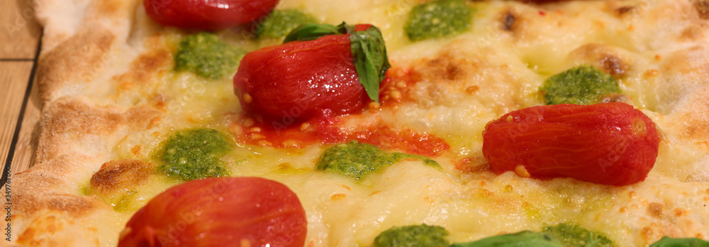 detail of Italian pizza with small red tomatoes pesto basil and detail of Italian pizza with small red tomatoes pesto basil and
