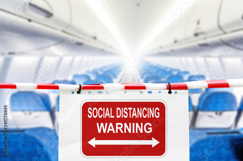 social distancing warning sign in airplane cabin against blurred passenger plane compartment background. Coronavirus disease COVID-19 new travel rules. Keep social distance banner concept