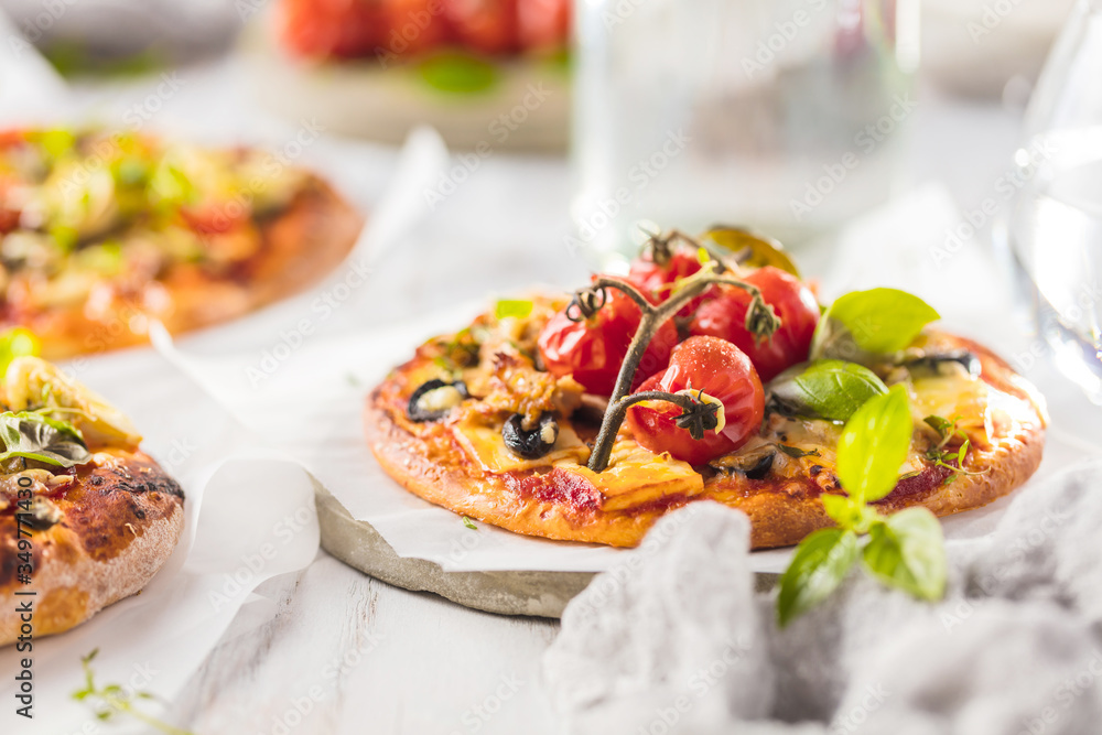 Fototapeta premium gourmet pizza with tomatoes, olives and basil leaves on wooden table