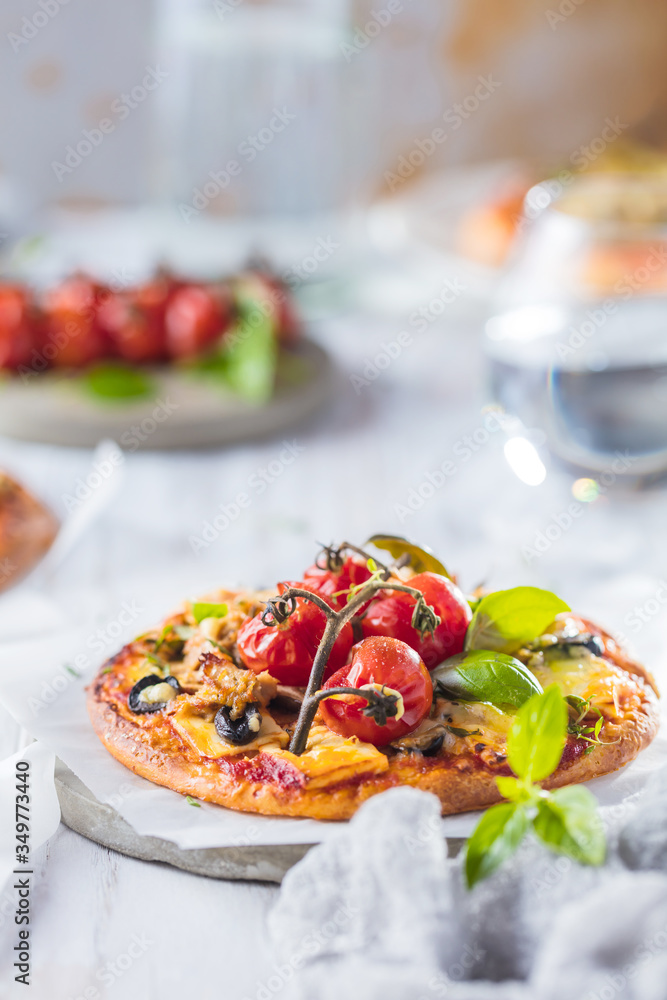 gourmet pizza with tomatoes, olives and basil leaves on wooden table gourmet pizza with tomatoes, olives and basil leaves on wooden table