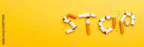 31 May of World No Tobacco Day, no smoking close up word STOP spelled text of the pile cigarette or tobacco on yellow background with banner copy space, and Warning lung health concept