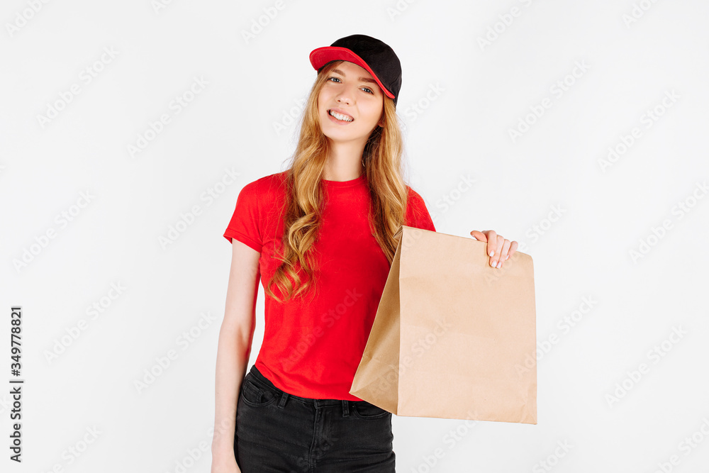 A uniformed courier holding a paper bag with food on a white background. The concept of home delivery A uniformed courier holding a paper bag with food on a white background. The concept of home delivery