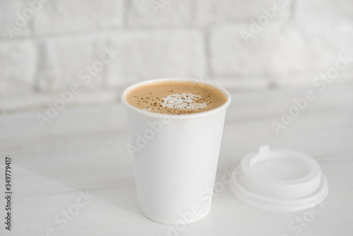 cappuccino in a white glass on a white table against a white brick wall