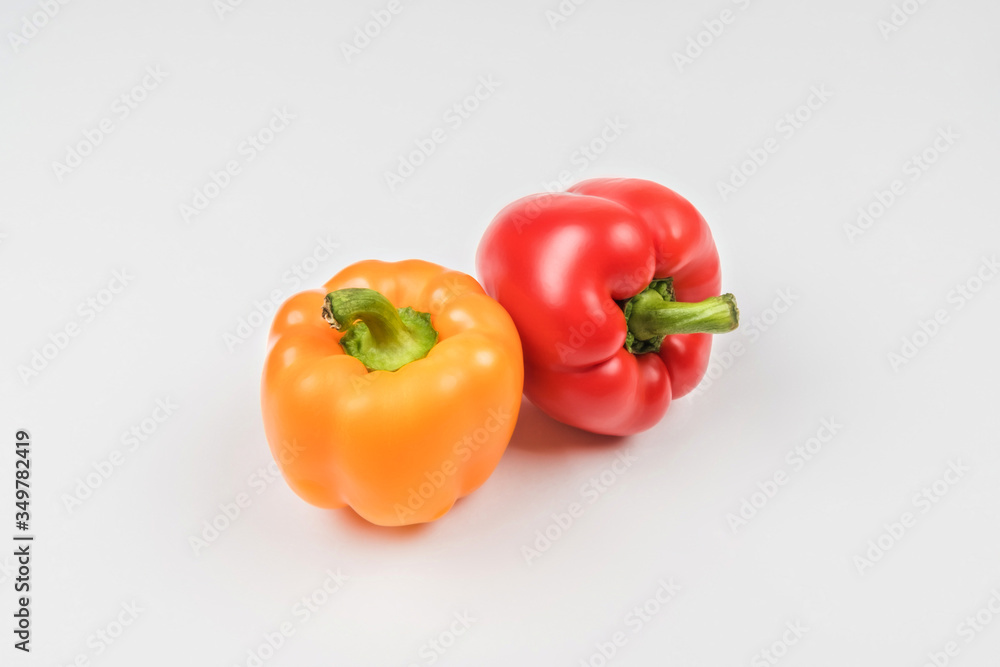 Two bell peppers orange and red on a light background. Two bell peppers orange and red on a light background.