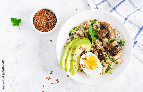 Breakfast oatmeal porridge with green herbs of mushrooms, boiled egg, avocado and flax seeds. Healthy balanced food. Top view, overhead,  copy space