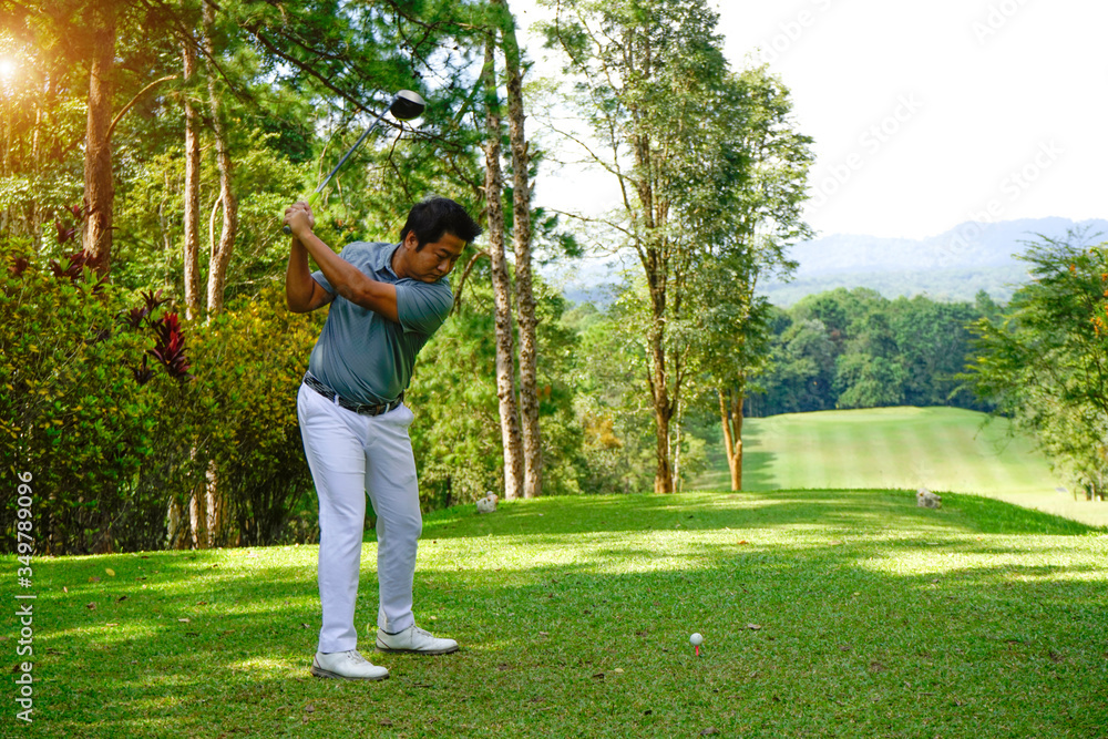 Golfer driving golf ball on beautiful golf course with clear blue sky in the mountains.