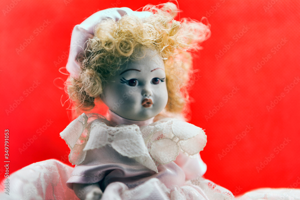 Fototapeta premium Beautiful vintage porcelain doll portrait with white dress blond hairs and and sweet glance