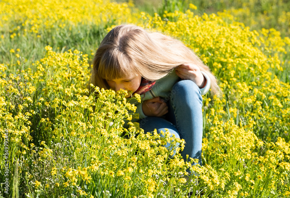 Cute girl sniffs yellow flowers in a summer meadow Cute girl sniffs yellow flowers in a summer meadow