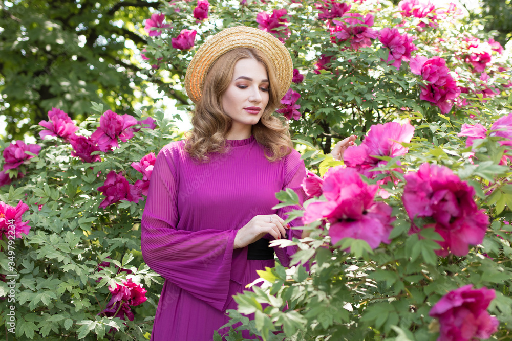 Young woman in straw hat among flowering peonies Young woman in straw hat among flowering peonies