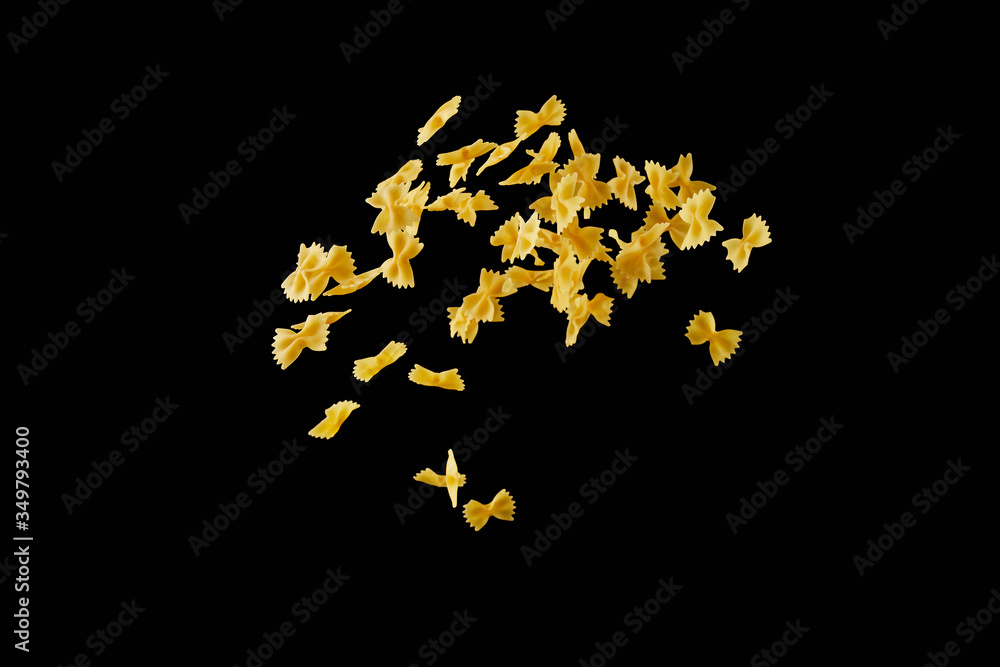 Italian flying raw pasta isolated on black background. macaroni farfalle falling.