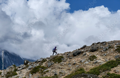 Active woman hiker goes up at Himalaya mountains cloudy landscape. Travel sport lifestyle concept