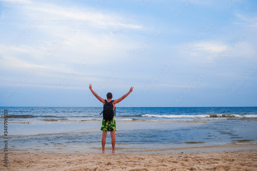 man with a backpack stands back with hands up background the ocean man with a backpack stands back with hands up background the ocean