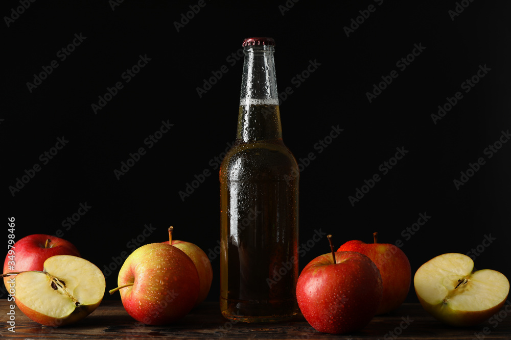 Composition with cider and apples on wooden table against black background Composition with cider and apples on wooden table against black background