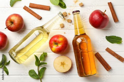 Composition with cider, cinnamon and apples on white wooden background