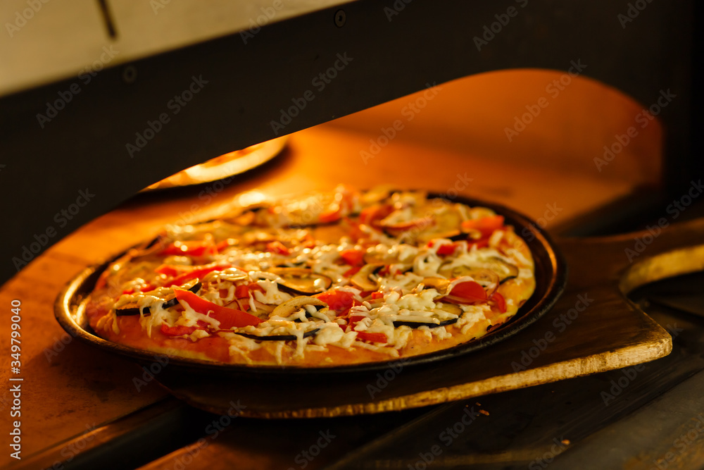 Baking a pizza in oven. Hot pizza in a dish on a shovel in a furnace. Baking a pizza in oven. Hot pizza in a dish on a shovel in a furnace.