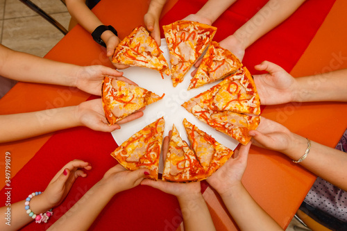 Kids hands sharing a pizza taking a slices