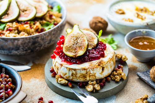 close-up view of tasty healthy dish with fruits  nuts  honey  camembert cheese  couscous and pomegranate seeds on wooden table