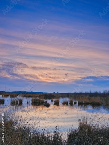 Colorful sky and colorful water in lake reflected in evening  focus on grass in foreground