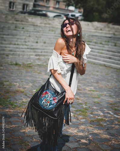 Girl with a fringe bag. fringed girl. Joyful girl holding a big black leather bag with fringe and color pattern. The concept of emotions and pleasures. Copy space for text.