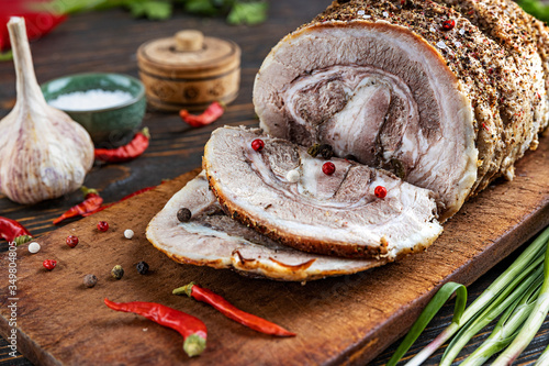 Foto Tasty baked pork sliced on slices on a wooden board, next to it, greens and spices, closeup, shallow depth of field, selective focus