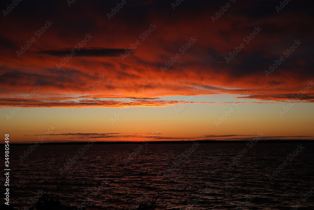 Fototapeta premium Colorful landscape at sunset.Ornate, lush, voluminous clouds cleared the horizon to the sun falling in a glittering ripple of water.The struggle of colors over the lake at the end of the day.Russia