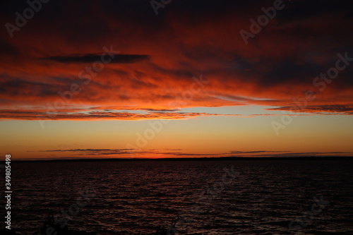 Colorful landscape at sunset.Ornate, lush, voluminous clouds cleared the horizon to the sun falling in a glittering ripple of water.The struggle of colors over the lake at the end of the day.Russia
