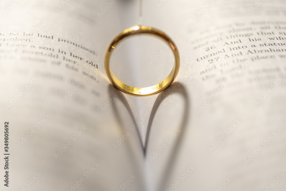 A wedding Ring on the bible with shadow of heart shape on the page A wedding Ring on the bible with shadow of heart shape on the page