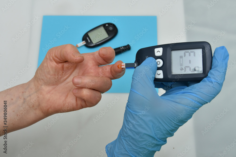 Doctor checking diabetic patient's blood sugar level with digital glucometer Doctor checking diabetic patient's blood sugar level with digital glucometer