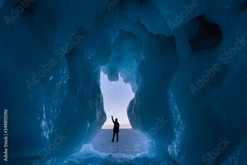 A traveller standing in front of ice cave in Baikal frozen lake in winter season, Siberia in Russia