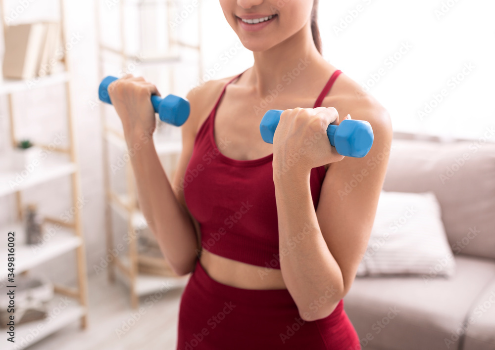 Unrecognizable young girl working out with weights, lifting dumbbells at home, closeup Unrecognizable young girl working out with weights, lifting dumbbells at home, closeup