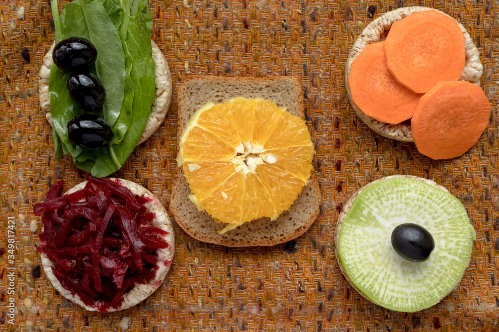 vegetarian sandwiches. on grain loaves lie. repeating the shape of the circle radishes, green radishes, carrots, beets cut into strips, olives, sorrel and orange. it harmonizes with a warm textured da vegetarian sandwiches. on grain loaves lie. repeating the shape of the circle radishes, green radishes, carrots, beets cut into strips, olives, sorrel and orange. it harmonizes with a warm textured da