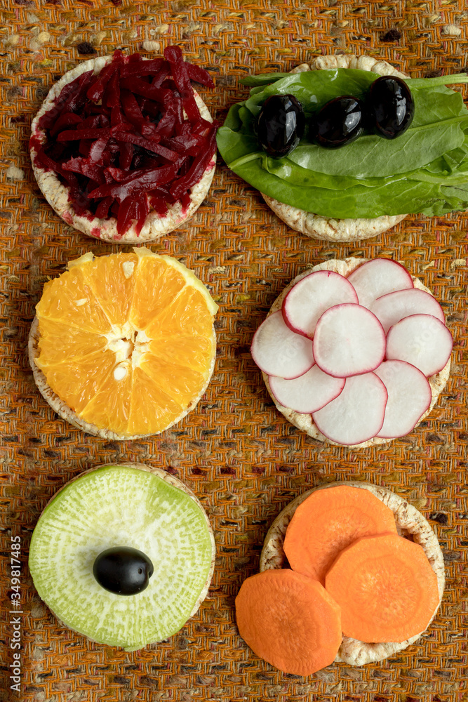 vegetarian sandwiches. on grain loaves lie. repeating the shape of the circle radishes, green radishes, carrots, beets cut into strips, olives, sorrel and orange. it harmonizes with a warm textured da
