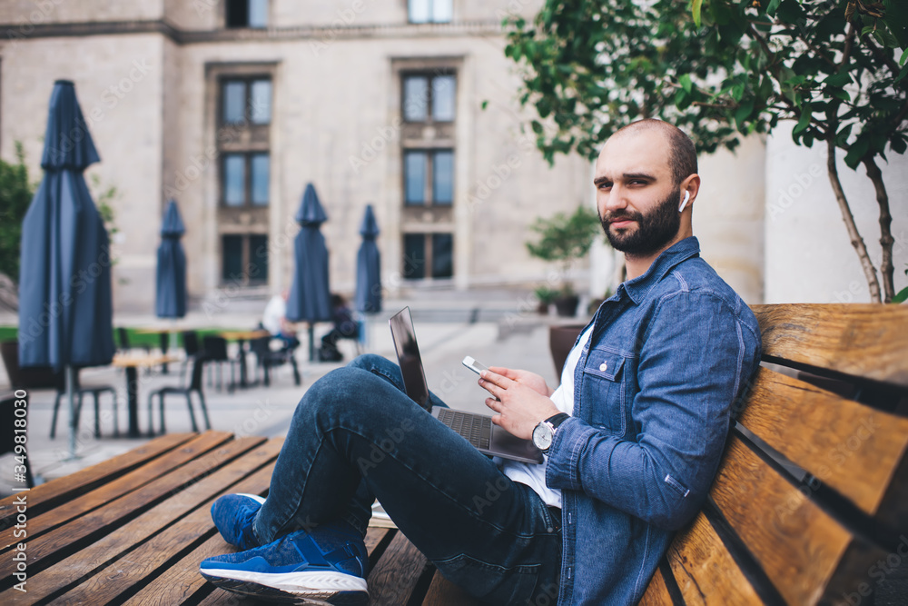 Modern young man with gadgets sitting next to street cafe Modern young man with gadgets sitting next to street cafe