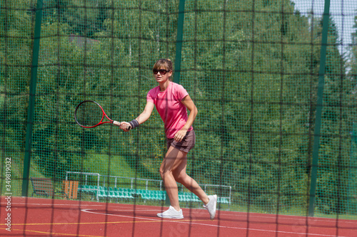 Female tennis player preparing to hit a forehand. View through net.