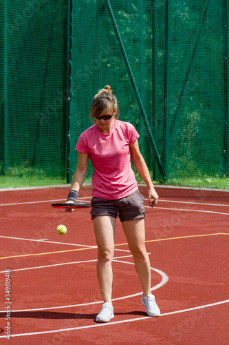 Female tennis player bouncing tennis ball on a court