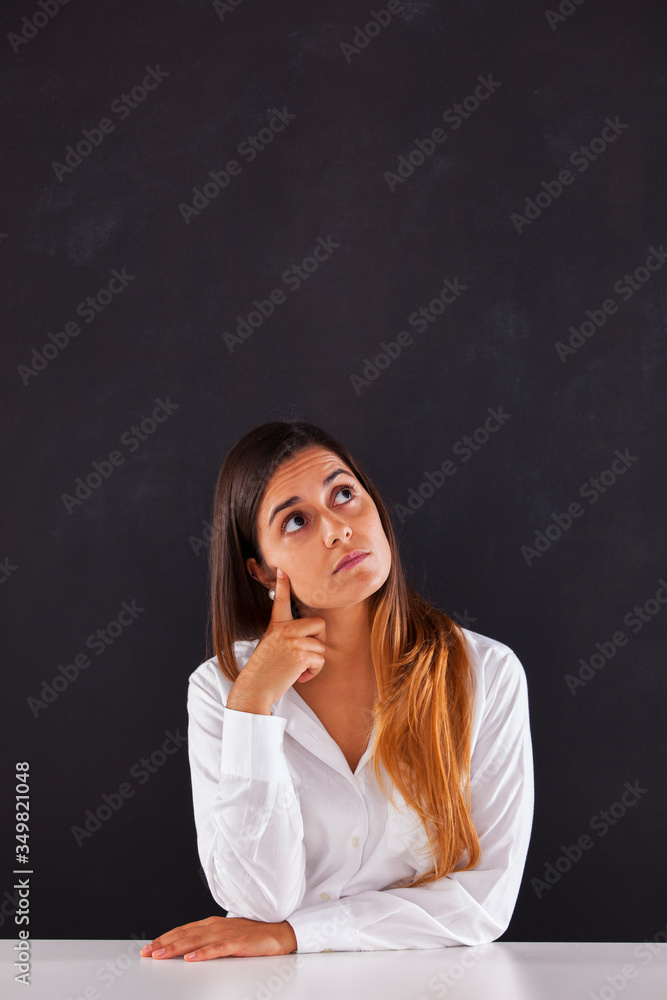 Woman thinking next to a blackboard Woman thinking next to a blackboard