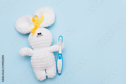 toy bunny with a toothbrush on blue background . copy space