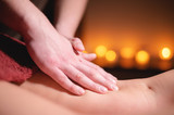 Close-up male hands of a professional massage therapist make professional anti-cellulite massage to a female client in a specialized salon in a dark room