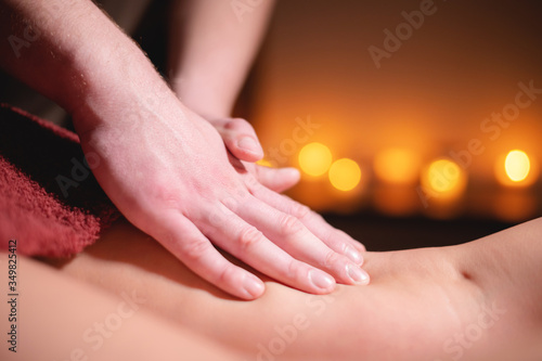 Close-up male hands of a professional massage therapist make professional anti-cellulite massage to a female client in a specialized salon in a dark room