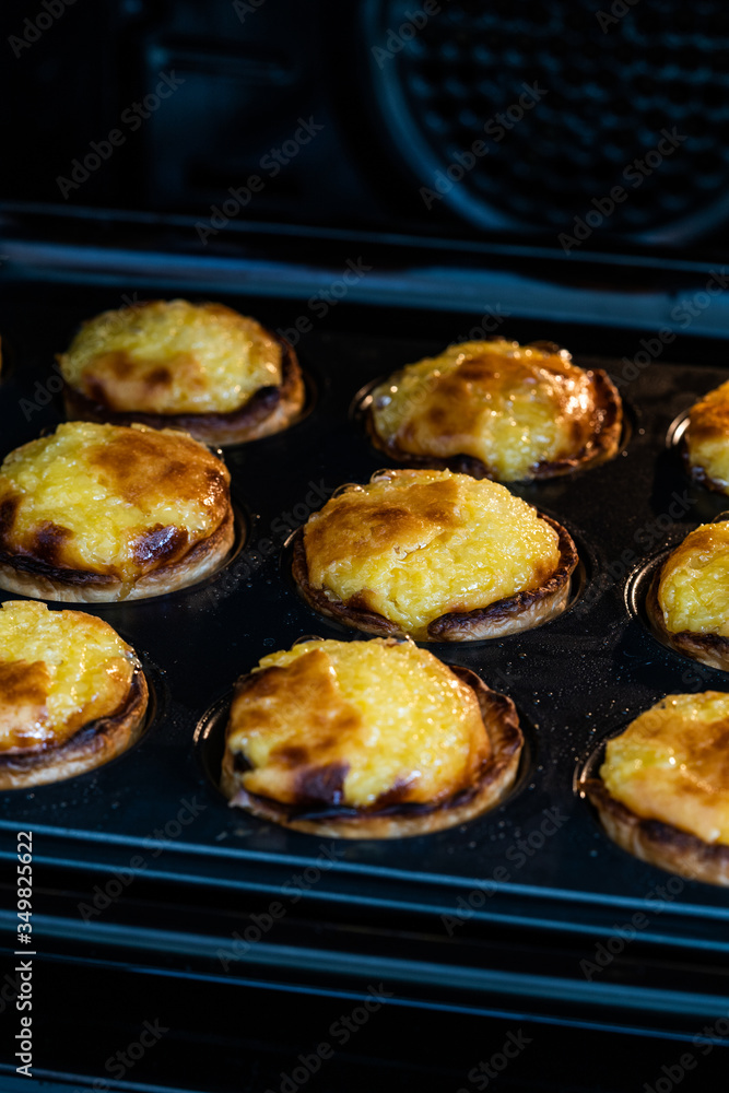 Pasteis de Nata or Belem Tart. Portuguese Custard made with Egg, Cinnamon, Sugar and Flour in Muffin Tray / Cupcake Mol in Oven.