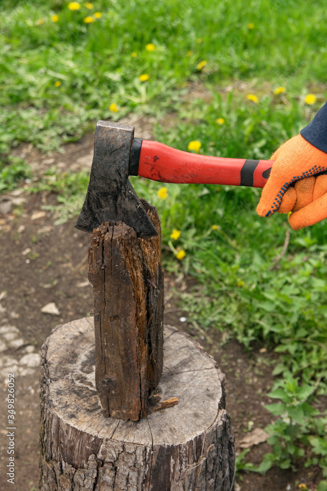Hands hold an ax and chop wood on a stump Hands hold an ax and chop wood on a stump