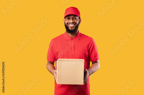 African American Delivery Man Holding Cardboard Box Standing In Studio