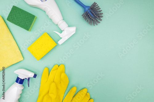 Cleaning tools and supplies on green background, top view.
