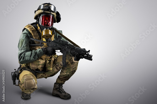 Soldier holding assault rifle. Uniform conforms to special services of the Russian Federation. Shot in studio. Isolated with clipping path on grey background © maximapryatin