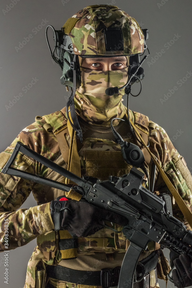 Fototapeta premium Soldier holding assault rifle. Uniform conforms to special services of the Russian Federation. Shot in studio. Isolated with clipping path on grey background