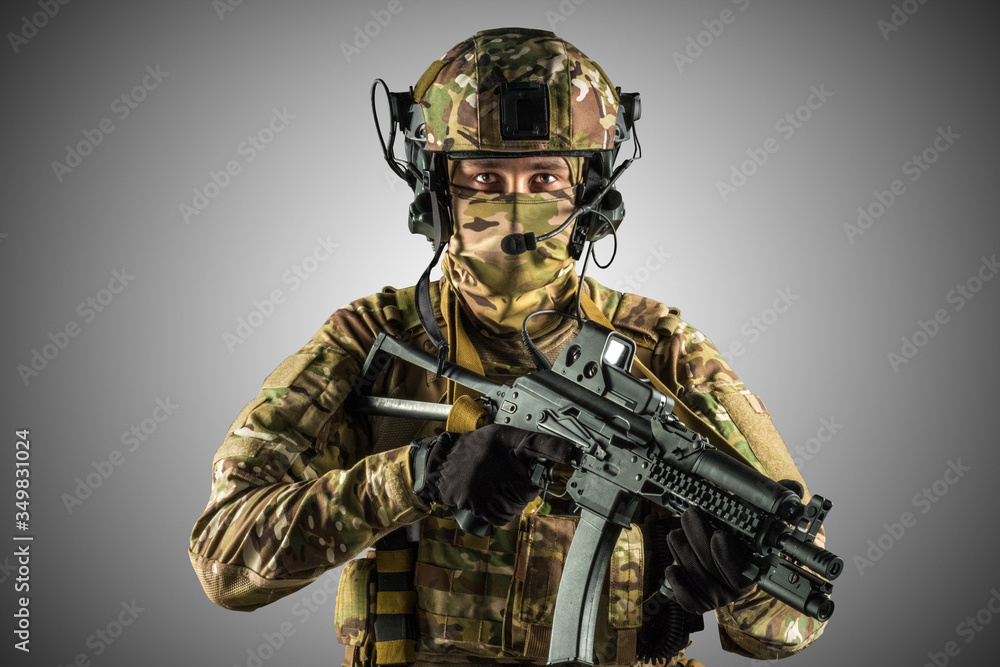 Naklejka premium Soldier holding assault rifle. Uniform conforms to special services of the Russian Federation. Shot in studio. Isolated with clipping path on grey background